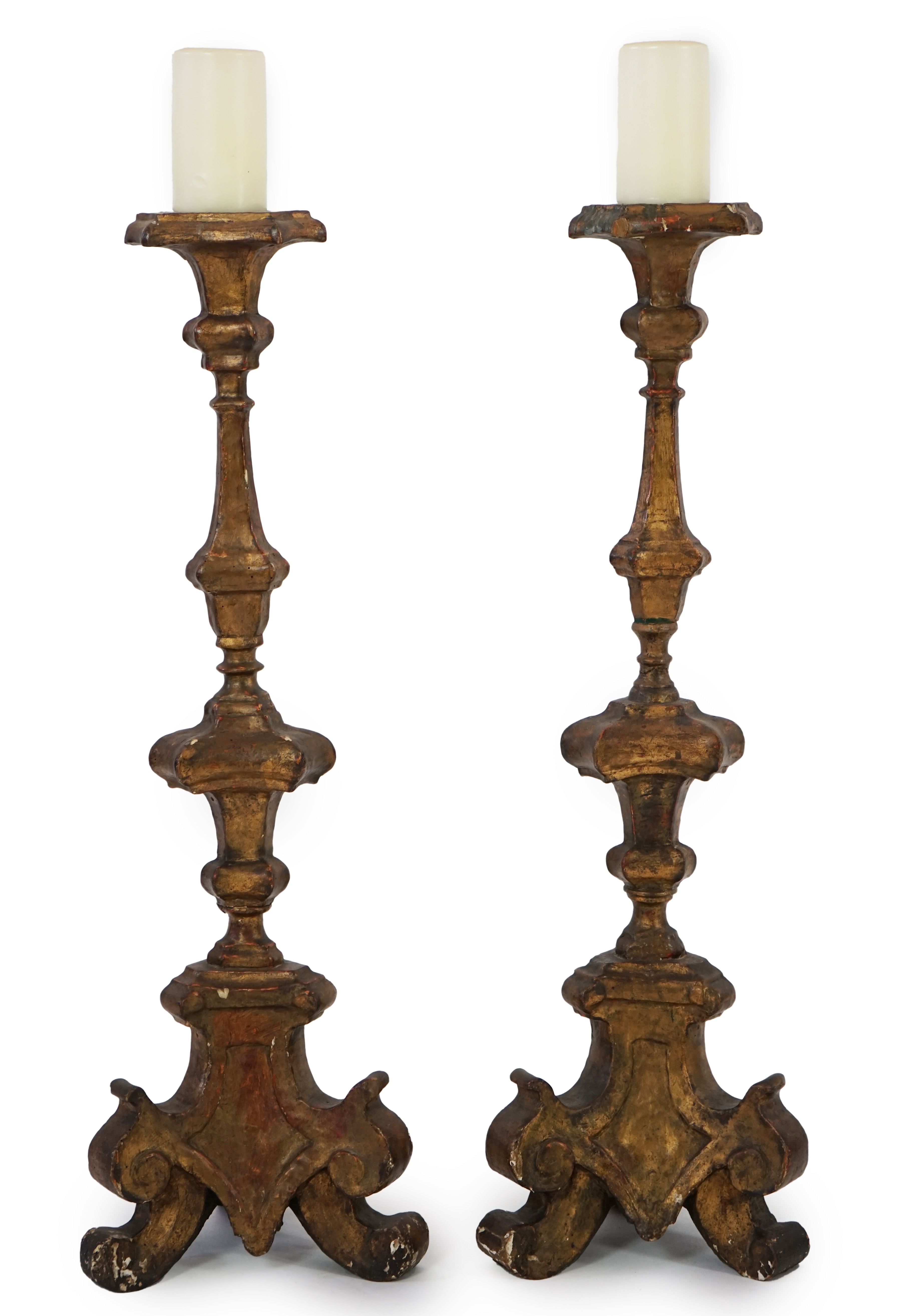 A pair of 18th century Italian giltwood candlesticks with knopped triangular stems and scroll feet, 89cm high. Condition - fair, Provenance- Brede Place, East Sussex, a former residence of the Frewen family from 1712-193